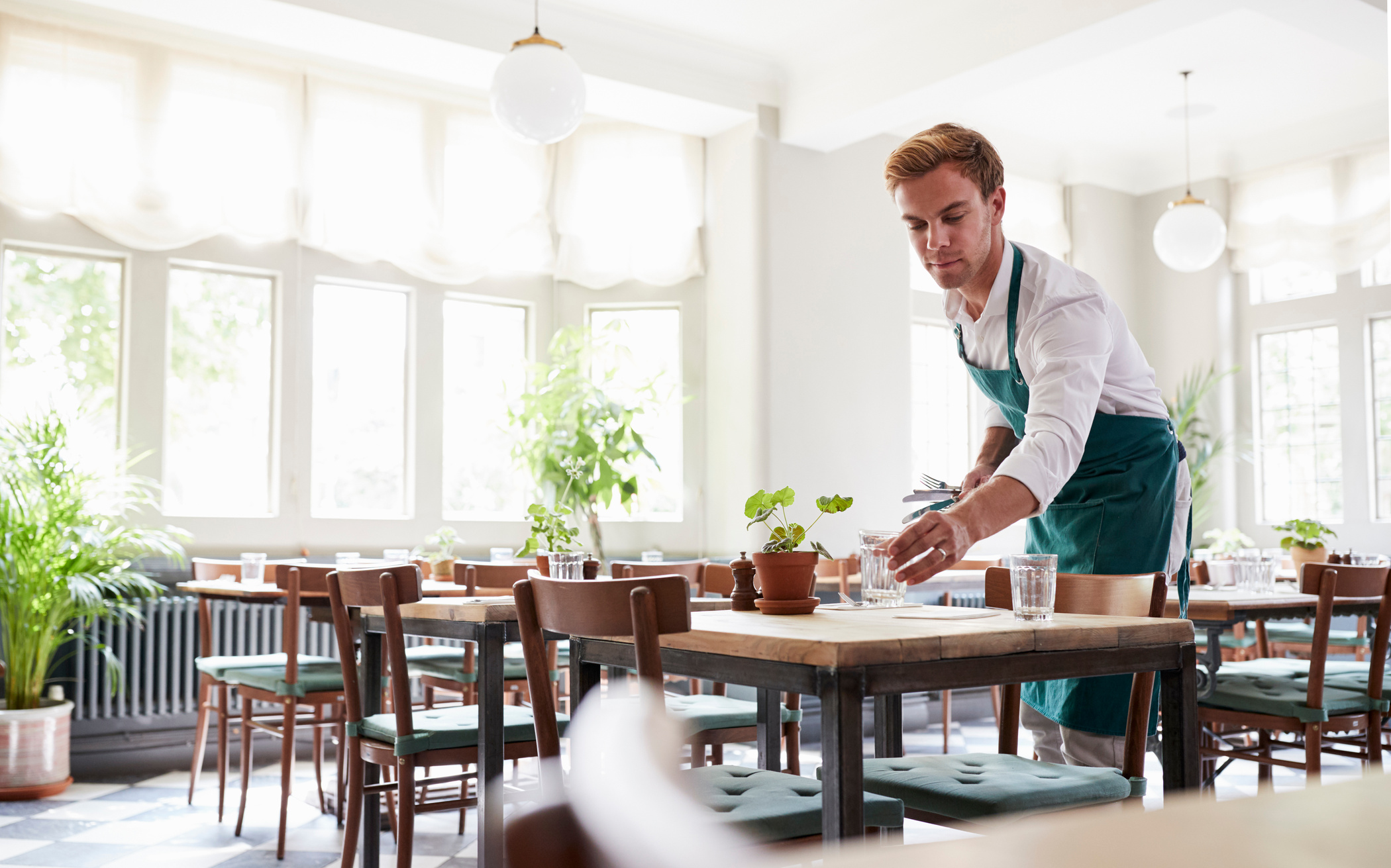 Waiter Laying Tables in Empty Restaurant